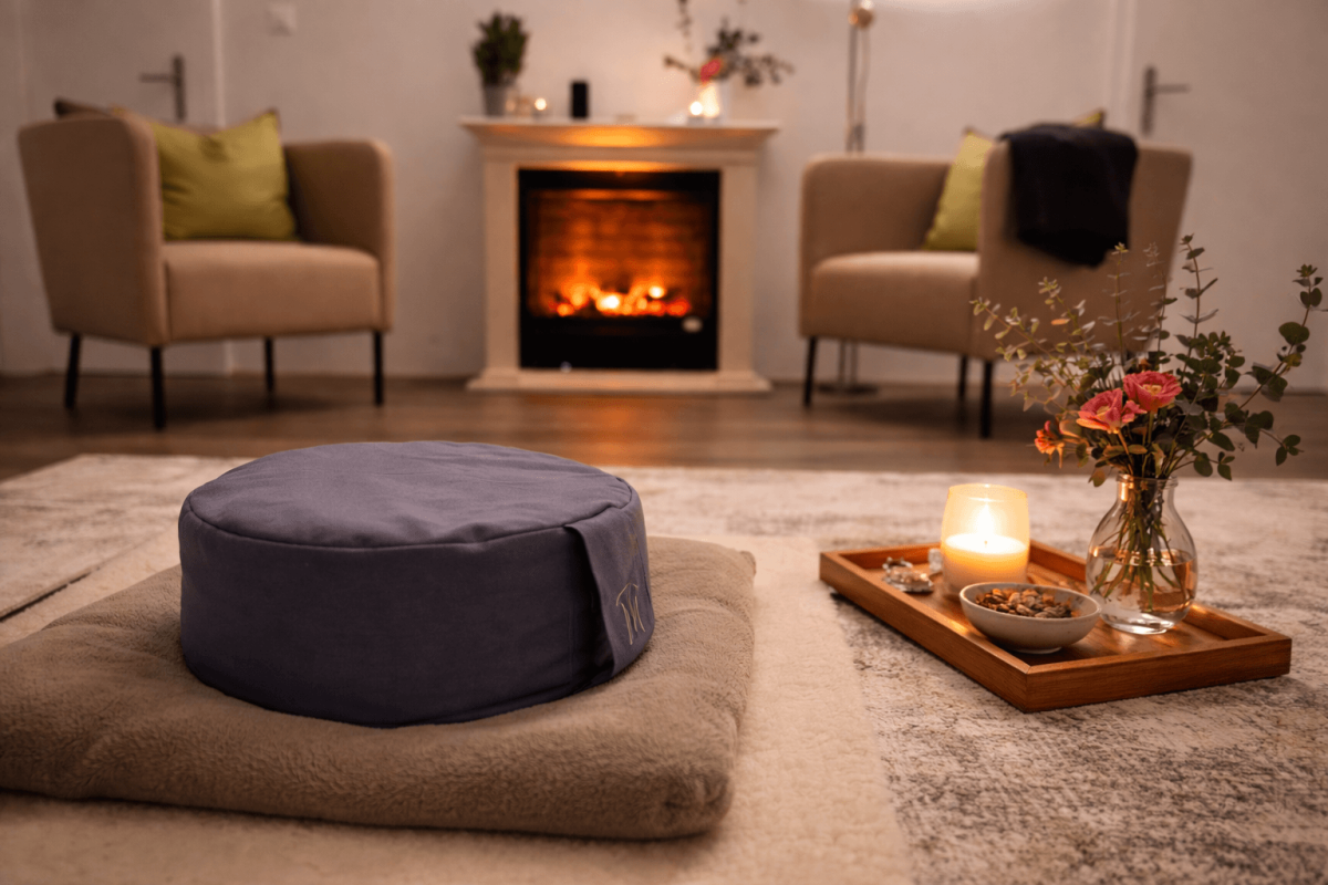 Ein gemütlicher Praxisraum mit Sitzkissen, Kaminfeuer und Kerzenlicht für Breathwork-Sitzungen und Entspannung bei Atem-Heilkraft.