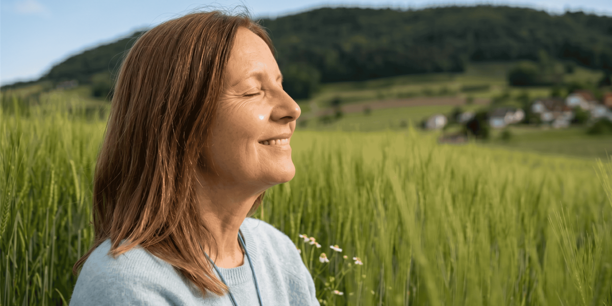 Frau in Diegten geniesst mit geschlossenen Augen die Natur und die Kraft der Zwerchfellatmung.