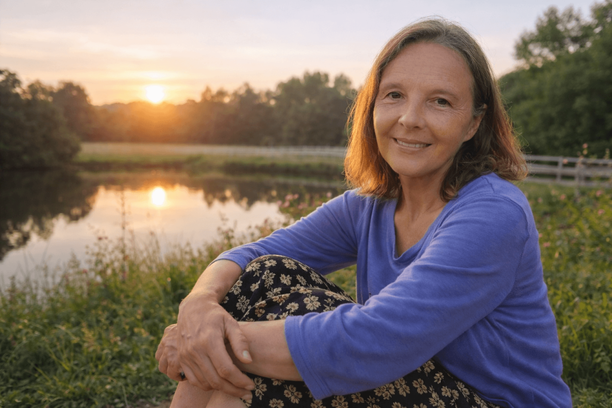 Sandra von Atem-Heilkraft sitzt lächelnd im Abendlicht an einem Teich.